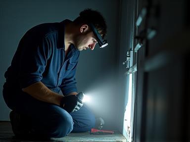 Emergency plumber with a flashlight in a dark area.